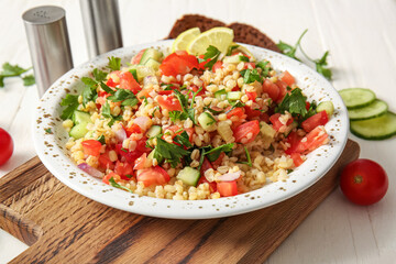Plate with delicious tabbouleh salad on table, closeup