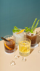 Set of alcoholic cocktails on podium with ice on colored background.