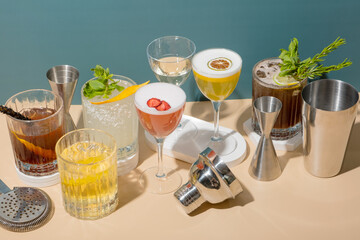 Composition with alcoholic cocktails and bar tools on podiums on colored background.