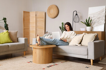 Young woman using laptop on sofa in living room