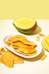Plate with slices of dried mango on yellow background