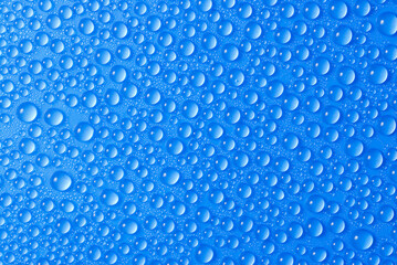 many small blue drops of water on a blue surface