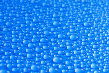 many small blue drops of water on a blue surface