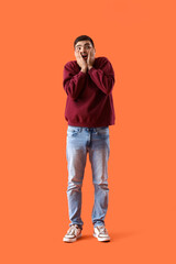 Afraid young man on orange background