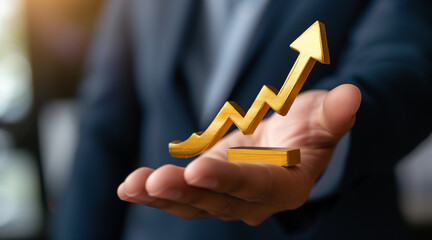 Close-up of a businessman's hand holding a golden colored upward arrow. concept of final and business success