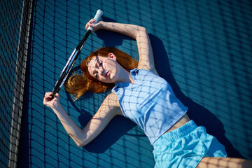 A female athlete with red hair poses on a tennis court 