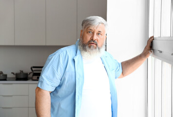 Afraid mature man near window in kitchen