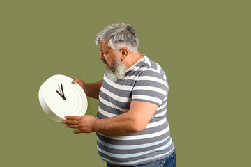 Afraid mature man with clock on green background