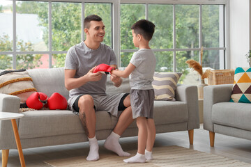 Obraz premium Young man and his little son with boxing glove at home