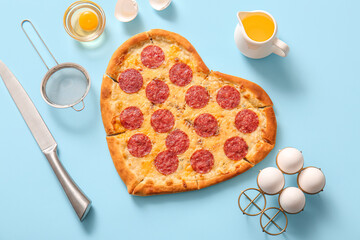 Tasty heart shaped pizza with fresh eggs and oil on blue background