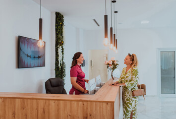 A beautiful blonde woman conversing with the dental clinic receptionist, scheduling an appointment for dental treatment with a bright smile - obrazy, fototapety, plakaty