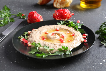 Plate of tasty baba ghanoush on black background