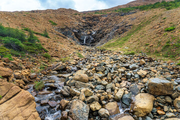 Tablelands in Gros Morne National Park, a Canadian national park and World Heritage Site in Newfoundland. An area where earth's mantle is exposed, peridotite rocks rich with iron rust, waterfall.