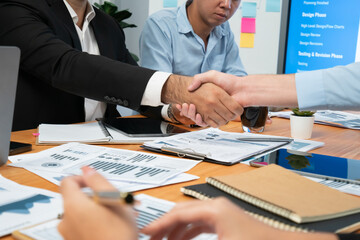 Cheerful meeting room, businesspeople celebrate with handshaking. Successful project was completed...