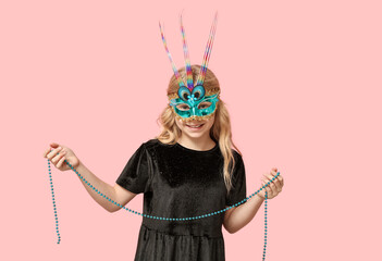Adorable little girl wearing carnival mask on pink background