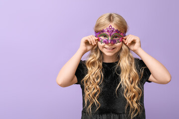 Funny little girl wearing carnival mask on lilac background