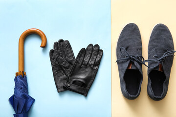 Male leather gloves, shoes and umbrella on color background