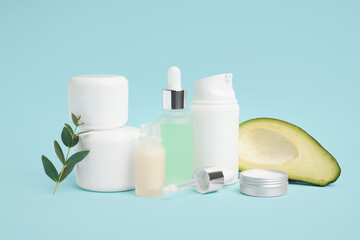 Set of different cosmetic products and fresh avocado on color background