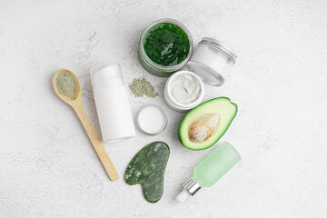 Composition with fresh avocado and jars of cosmetic products on light background