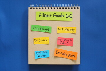Fitness goals concept. Checklist of goals in note pad in blue background with copy space.