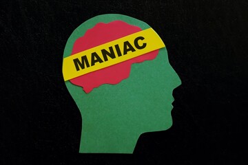 Human head profile with word maniac in dark black background. Psychological disorder warning...