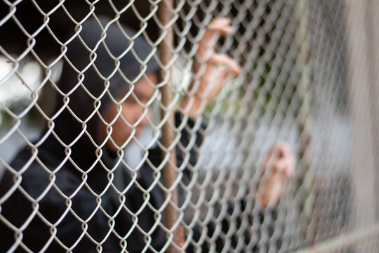 Detention of preteens inside the metal fence and wall because of their bad behavior and habits, freedom and human rights concept.