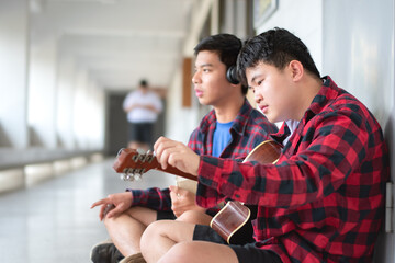 Group of asian secondary school students spending their freetimes by playing acoustic guitar in...