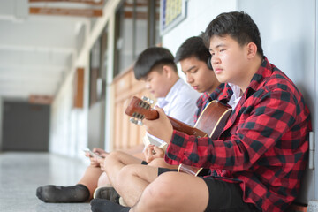 Group of asian secondary school students spending their freetimes by playing acoustic guitar in...