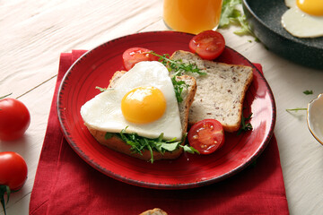 Plate with tasty fried egg, toasts, tomatoes and arugula on light wooden background, closeup