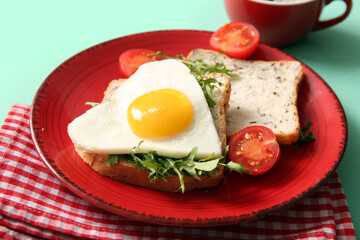 Fototapeta na wymiar Plate with tasty fried egg, toasts, tomatoes and arugula on turquoise background, closeup