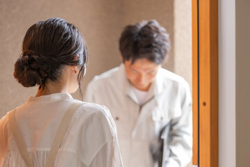 自宅に訪問した業者を出迎える主婦の後ろ姿
