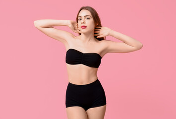 Fototapeta premium Sexy young woman in black underwear on pink background