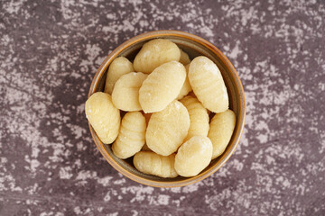 Bowl with delicious gnocchi on grunge background