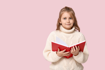 Little girl reading book on pink background