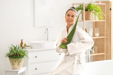 Beautiful young happy woman in bathrobe with aloe vera at home