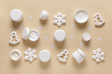 Fototapeta na wymiar Jars of cream with decorative snowflakes and fir trees on beige background