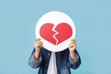 Handsome young man with heart dislike icon on blue background