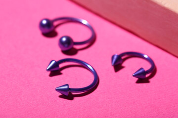 Circular barbells for piercing on pink background