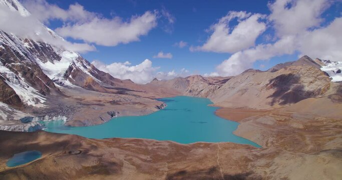 Drone shot of World's highest lake at Annapurna circuit Nepal, World's highest altitude lake Tilicho surrounded by mountains and clouds, blue lake, snow, sunny weather adventure 4K