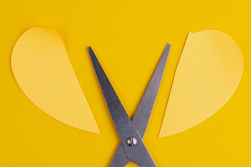 Stationery scissors and a paper heart cut in half. Background with selective focus and copy space