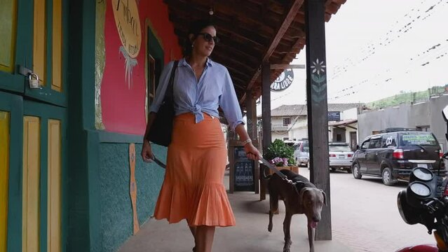 Woman walks her dog on colorful charming street in Samaipata, Bolivia