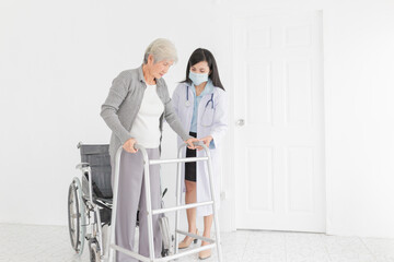 walk training and rehabilitation process, old asian stroke patient learning to uses walker with female asian doctor in hospital, elderly healthcare promotion