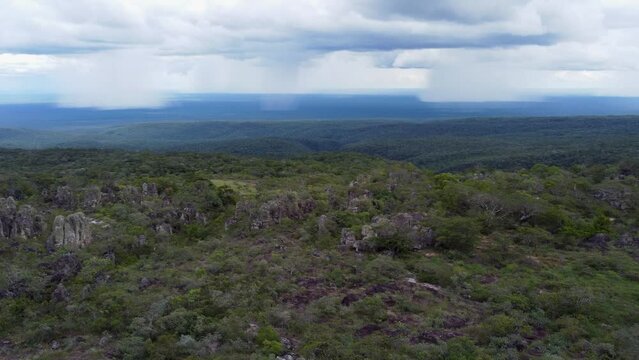 Rugged landscape flyover with cloud burst rain storms in distance