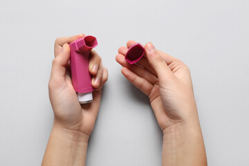 Child's hands with asthma inhaler on white background