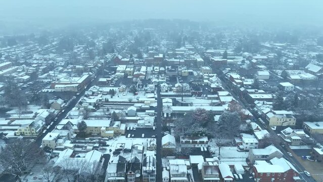 Snow covered town. High aerial orbit during snow storm above quaint historic American town.