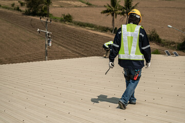 Engineer walking at roof top of warehouse industry at urban rural. Worker operating for inspection and construction.