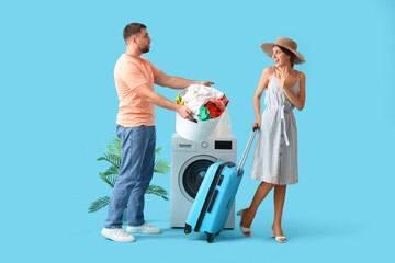 Young woman on vacation and her displeased husband doing laundry on blue background