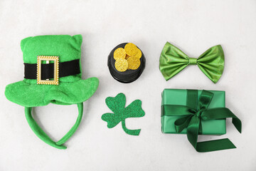 Pot with golden coins, gift box and leprechaun hat on light background. St. Patrick's Day...