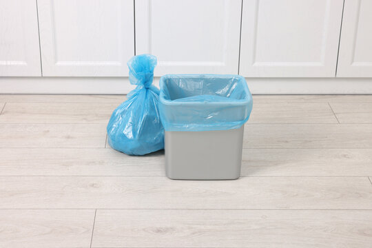 Plastic garbage bag and trash can indoors