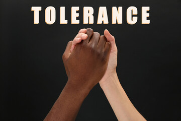 Tolerance, support and cooperation concept. Woman and man of different races clasping hands on...